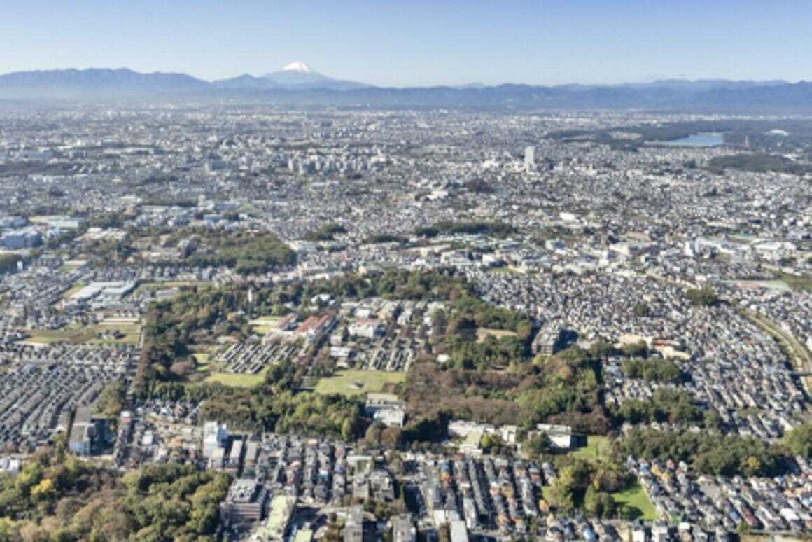 多磨ぜんしょう園の航空写真。緑に囲まれたぜんしょう園の敷地を中心に、山々の向こうに雪を被った富士山が見えています。